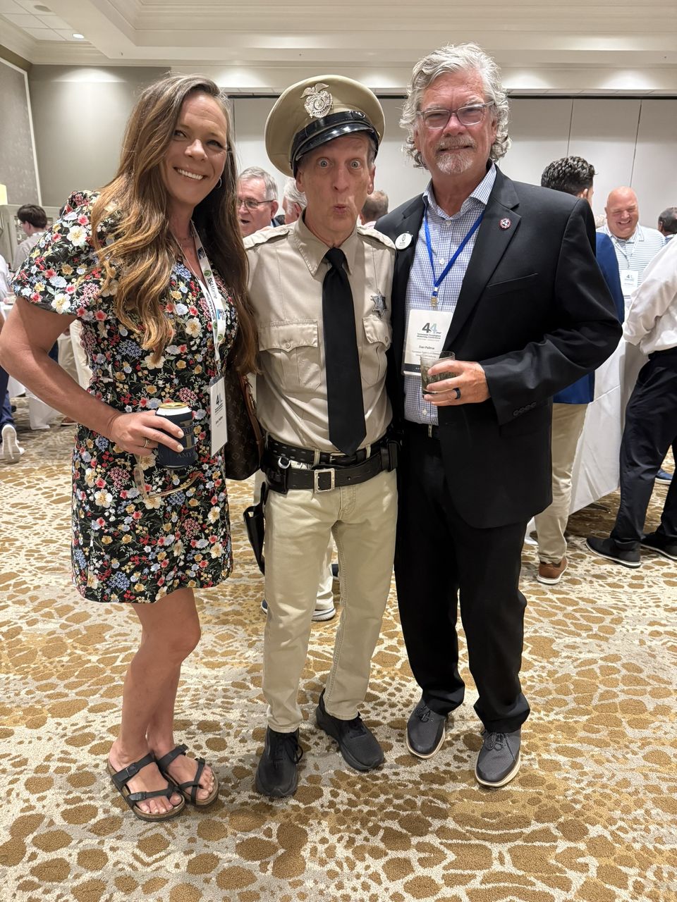 Three attendees pose together, one in a vintage uniform and campaign hat.