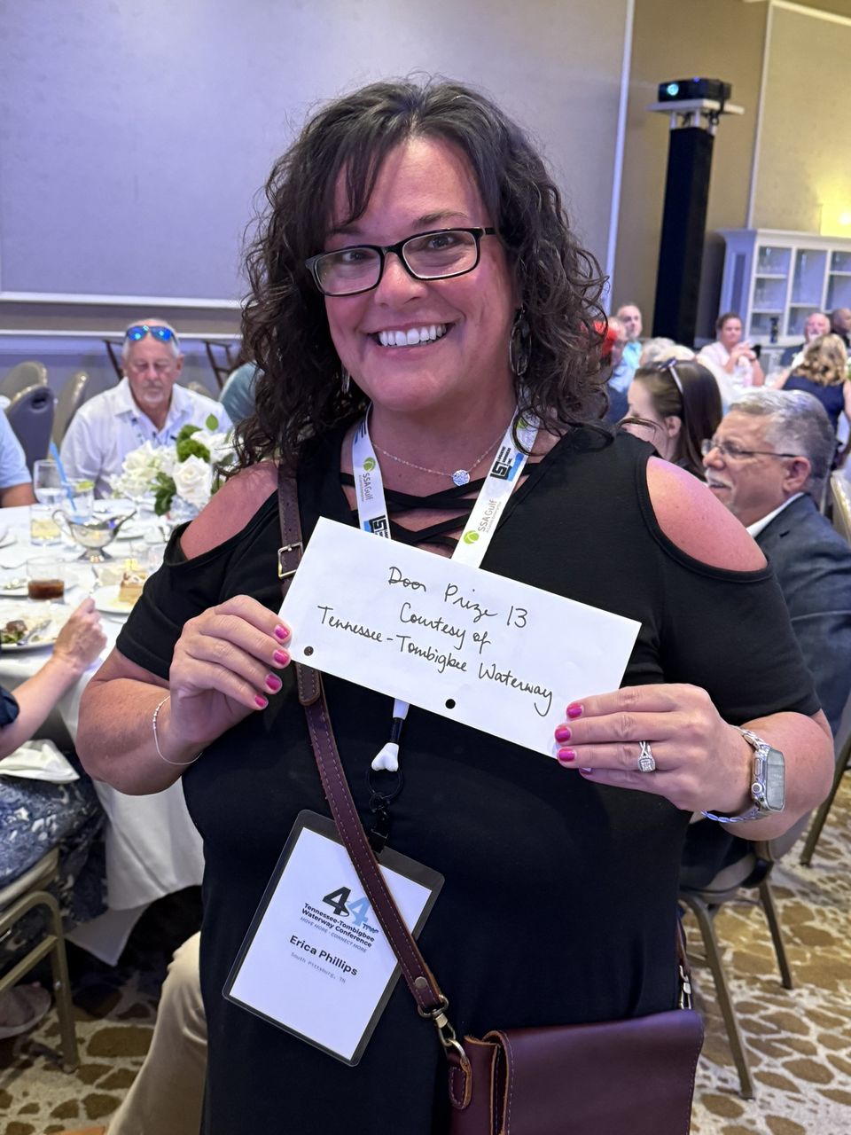 An attendee smiles and holds up a prize envelope.