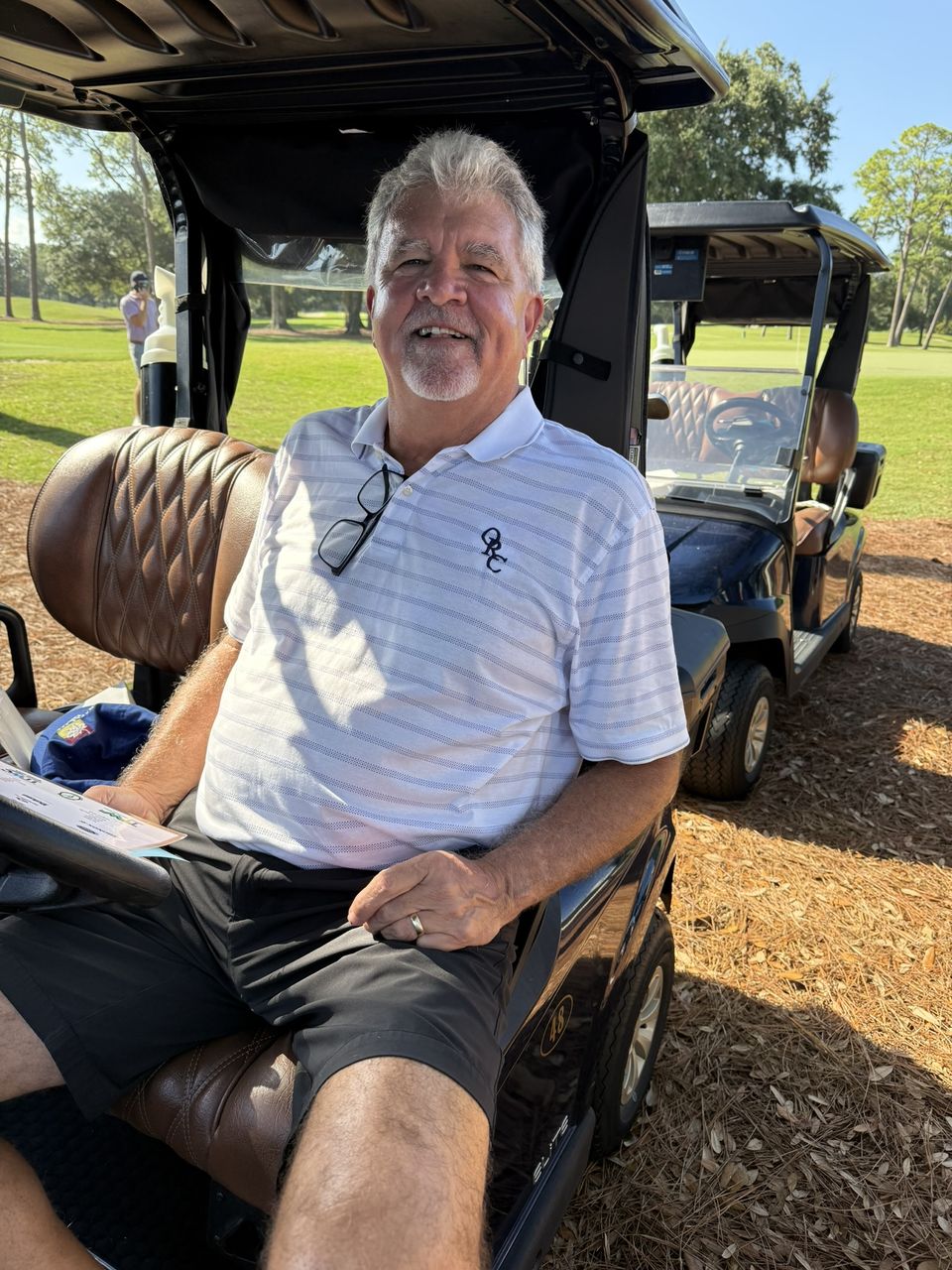 A golfer smiles from his cart.