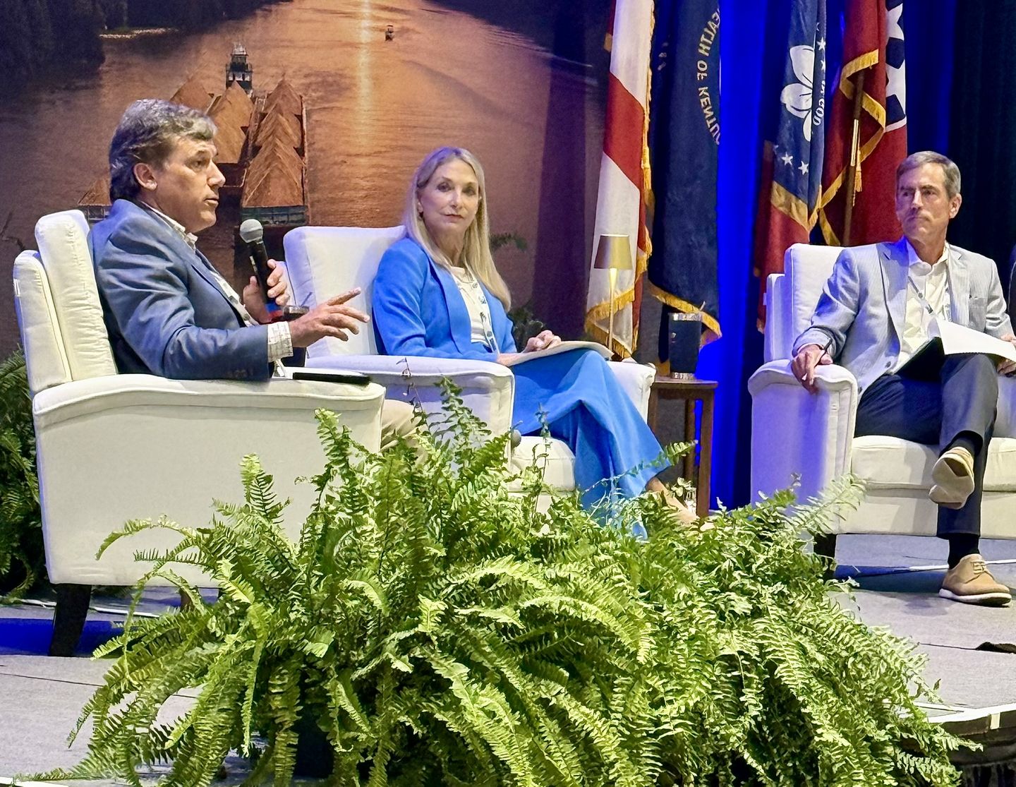 A three-person panel discussion on stage.