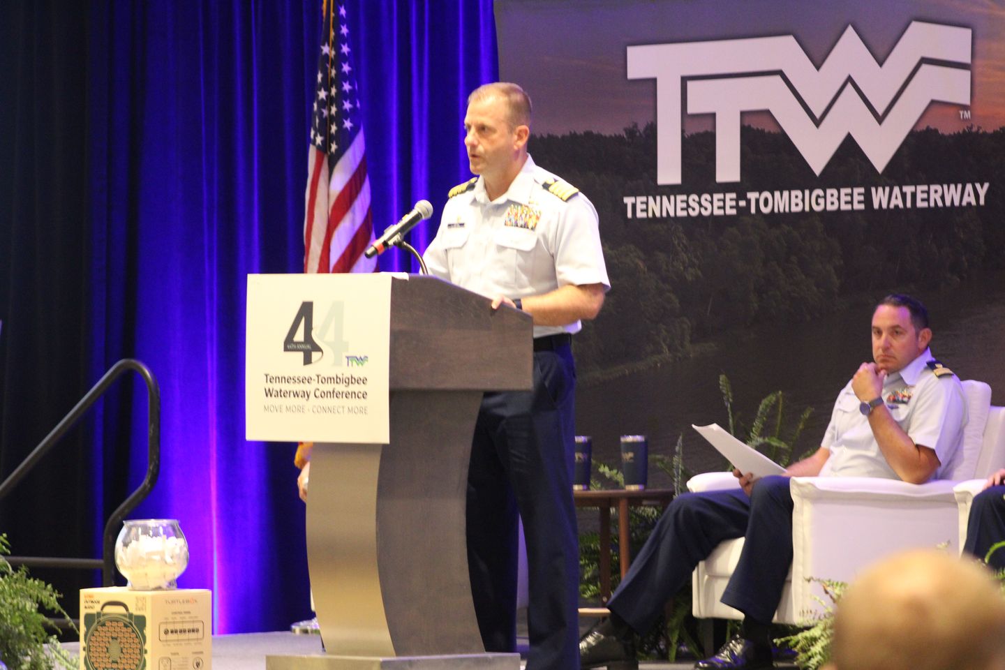 A Coast Guard officer speaks at the podium while a fellow panelist listens.