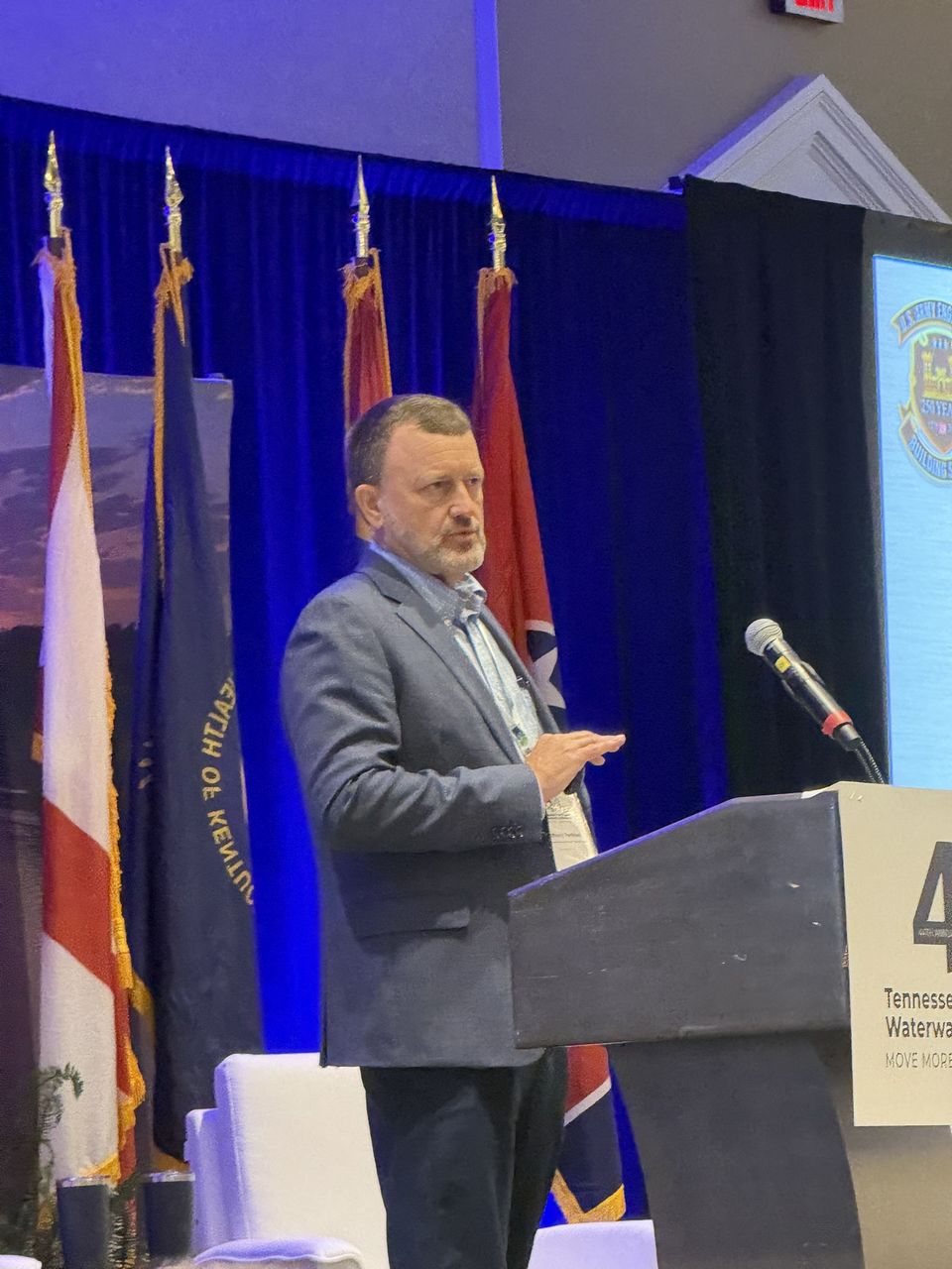 A speaker at the podium beside the state flags.