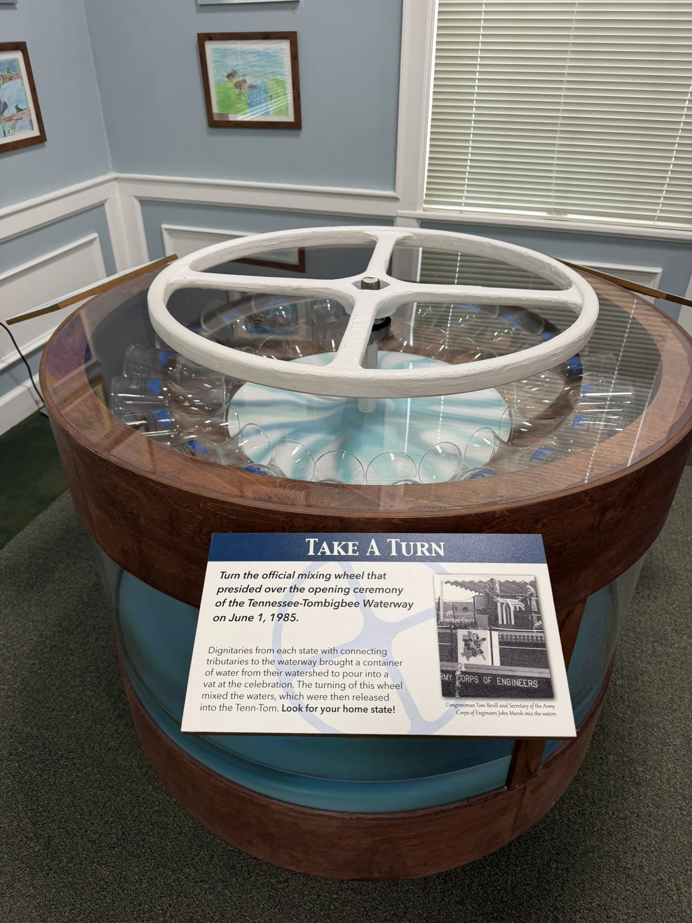 The museum's large white christening wheel above a round, water-filled display